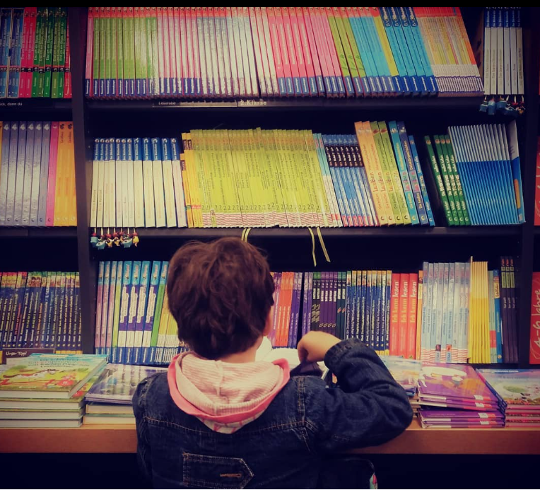 Ein Kind kniet vor einem Bücherregal in der Buchhandlung